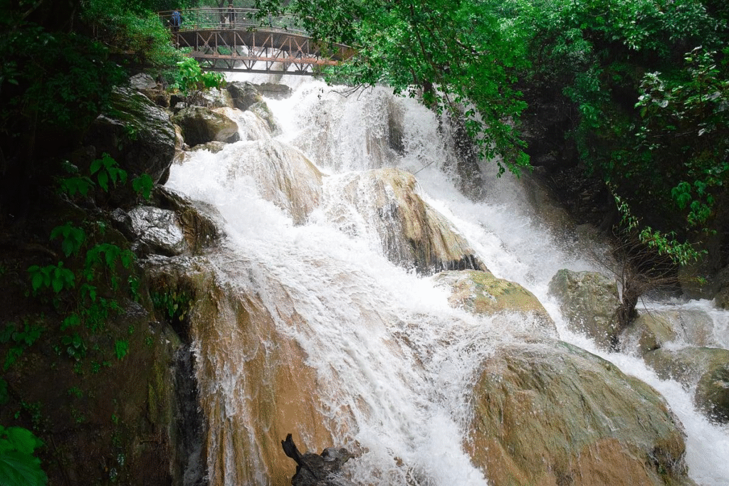 Neer Garh Waterfall flowing through green forest near Rishikesh
