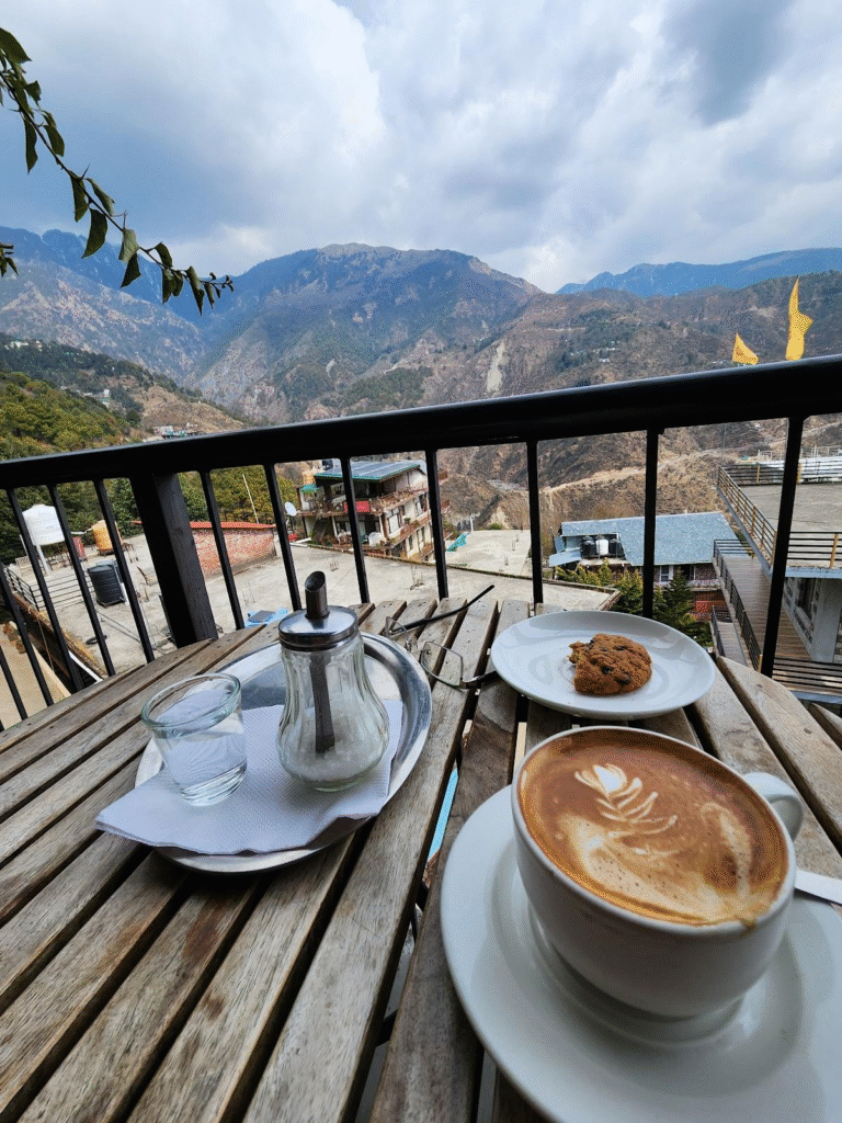 Cup of coffee on a wooden table at a café in Dharamshala with mountain view